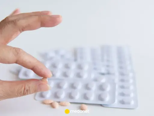 Szukasz co zamiast statyn na cholesterol? Dłoń trzyma tabletkę, w tle blistry leków.