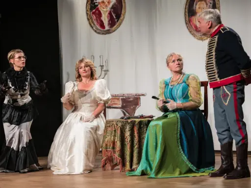 Damy w balowych sukniach i elegancki huzar na scenie.