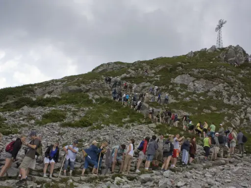 Tłum turystów wspina się na Giewont. Kolejka do wjazdu na szczyt jest długa, a cennik pewnie nie jest tani.