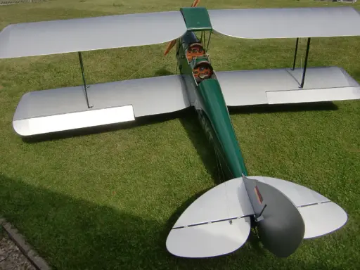 Ein detailgetreues Tiger Moth RC-Modellflugzeug mit silbernen Flügeln und grünem Rumpf steht auf einer grünen Wiese.