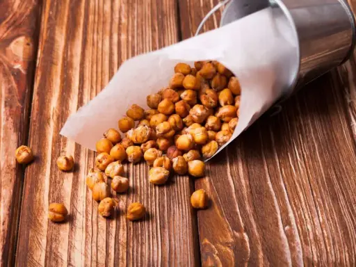 Ceci croccanti in friggitrice ad aria, versati da un cono di carta su un tavolo di legno.