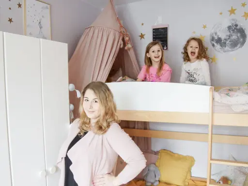 Wesołe dziewczynki w łóżku piętrowym w pokoju dla rodzeństwa. Mama uśmiecha się obok.