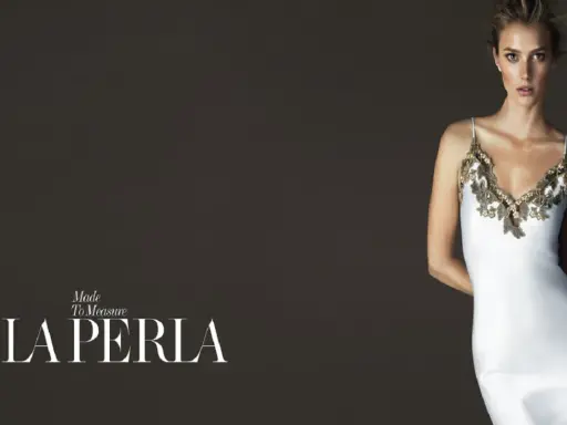 Model in a white slip dress with gold lace trim, with "LA PERLA" logo.