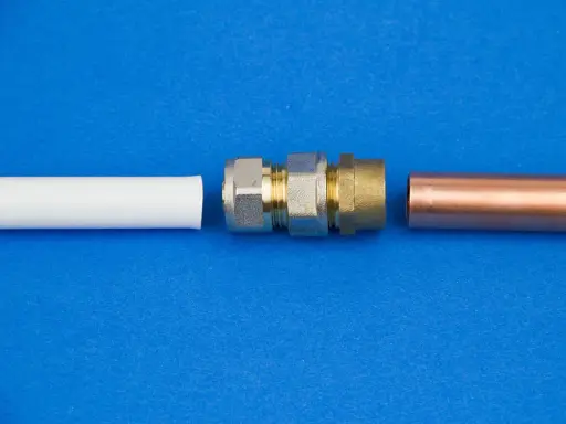 Raccordement de tuyaux : un coude 1/4 mâle femelle en laiton et un tube de cuivre à côté d'un tube blanc.