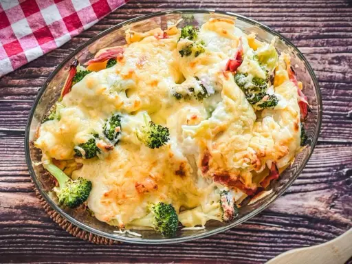 Heißer Brokkoli Nudel Auflauf mit geschmolzenem Käse in einer Glasschüssel, bereit zum Servieren.