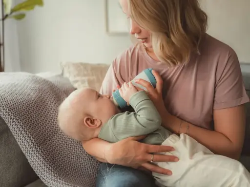 Mutter füttert Baby mit Flasche. Das Baby trinkt langsam, um die Verdauung zu unterstützen.