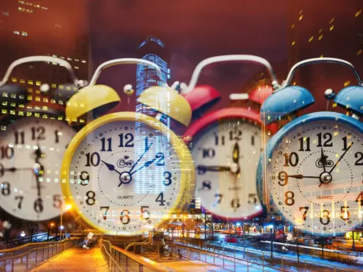 Wiele kolorowych budzików na tle nocnego miasta. 0404 znaczenie czasu, który nieustannie płynie.