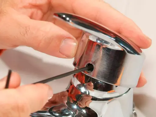 Mano ajustando un grifo monomando con llave Allen. Así es como funciona un grifo monomando.