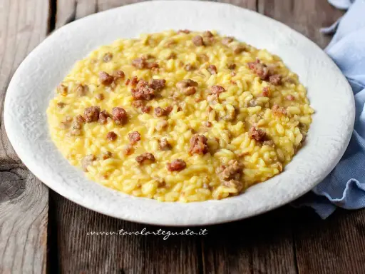 Un cremoso risotto con salsiccia, servito su un piatto bianco, pronto per essere gustato.
