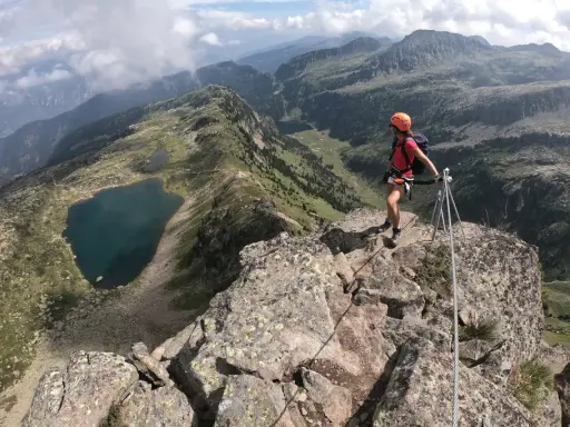 Escursionista in cima a una cresta rocciosa con vista sui laghi di Bombasel e sulle montagne circostanti.