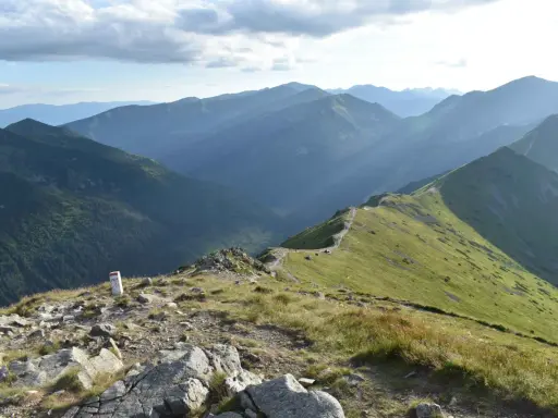 Widok na pasmo górskie Tatr z zielonymi zboczami i kamienistym szlakiem.