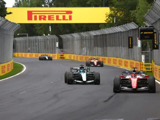Coches de Fórmula 1 compiten en una curva, con el cartel de Pirelli al fondo. ¡Emocionantes noticias de Fórmula 1!
