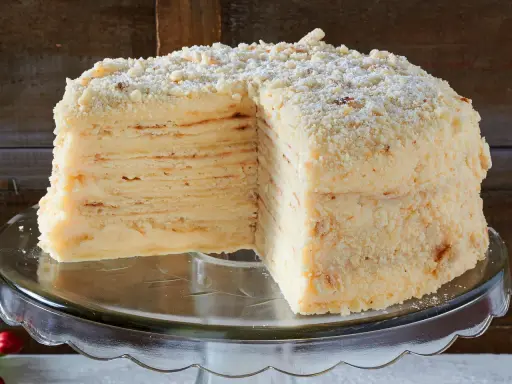 Ein aufgeschnittener Napoleon Kuchen mit vielen dünnen Schichten und cremiger Füllung, bestreut mit Krümeln.
