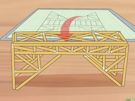 Un modelo de puentes de madera se construye sobre un plano de ingeniería.