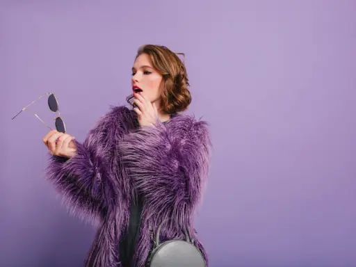 Chica con abrigo morado y maquillaje vibrante, lista para un evento.