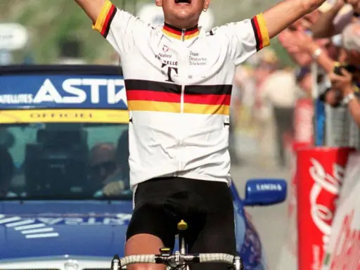 Jubelnder Radfahrer im Trikot des Teams Deutsche Telekom, ein deutscher Tour de France Sieger, mit erhobenen Armen vor jubelnder Menge.