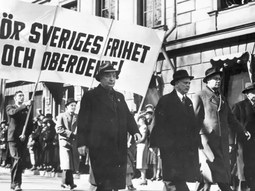 Män i hatt och rock marscherar med en banderoll: "För Sveriges frihet och oberoende!". En bild som speglar socialdemokraterna historia.