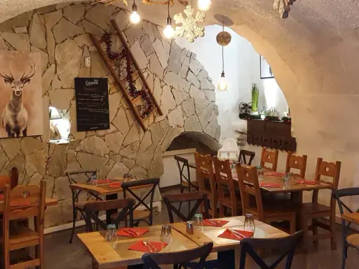 Ambiance chaleureuse dans un des restaurants de Briançon. Murs en pierre, tables en bois, tableau de menu et décoration hivernale.