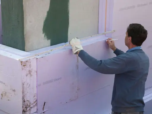 Mann markiert Styropor für Dämmung. Wichtig für Brandschutz und Wärmeschutz am Bau.