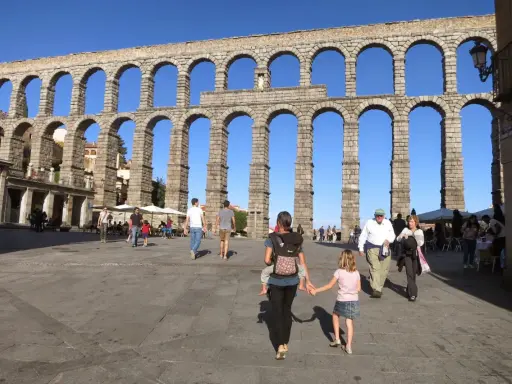 Familia pasea bajo el Acueducto de Segovia, un lugar ideal que ver en Segovia con niños.
