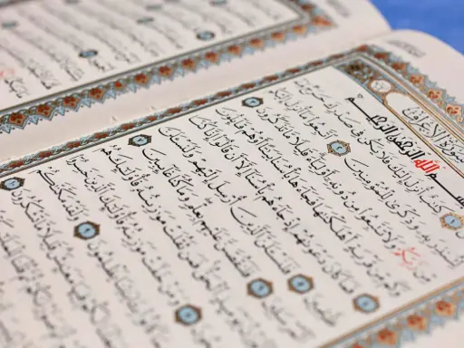 Ein aufgeschlagenes Korankonvolut mit arabischer Schrift und dekorativen Rändern. Es erinnert an die Lehren des Islams und die Geschichten von Jinn.