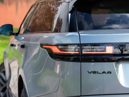 Detalle trasero de un Range Rover Velar plateado, mostrando sus luces LED y el emblema. Sus dimensiones son ideales para la ciudad y la aventura.