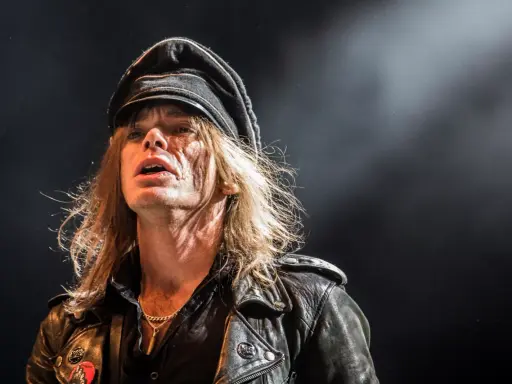 Nicke Andersson från Hellacopters, med sin karaktäristiska keps och läderjacka, fångad i ett intensivt ögonblick på scenen.
