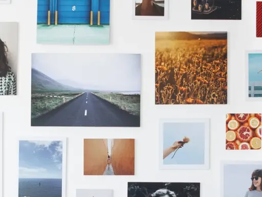 Un collage di fotografie su una parete bianca: paesaggi, ritratti, natura. Un'idea su come esporre fotografie in modo creativo.
