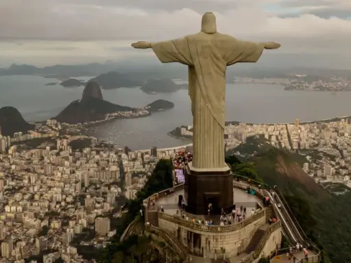 Majestatyczny pomnik Rio de Janeiro Jezus wita turystów, rozpościerając ramiona nad tętniącym życiem miastem i zatoką.