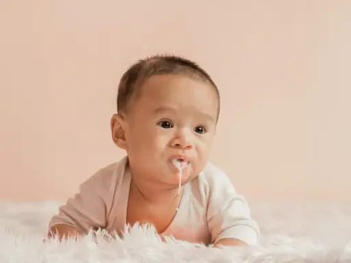 Söt bebis med mjölk runt munnen, ser ut som att bebis spyr mycket.