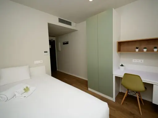 Habitación moderna con cama, armario verde y escritorio. Un espacio acogedor en Xior The Lofttown, listo para tu estancia.