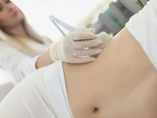 Ärztin untersucht Bauch einer Frau mit Ultraschall, um Schmerzen linke Seite Taille zu diagnostizieren.