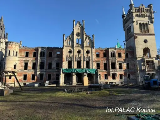 Ruiny pałacu w Kopicach, zniszczony zamek z ceglanymi ścianami i pustymi oknami, pod błękitnym niebem.
