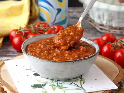 En skål med mustig bolognese, perfekt för ett gott bolognese recept. Färska tomater i bakgrunden.