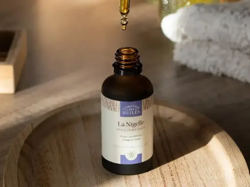 Une goutte d'huile de nigelle, aux propriétés anti inflammatoires, tombe dans un flacon. Idéal pour peaux à problèmes.