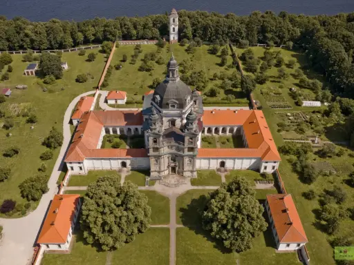 Litwa atrakcje: imponujący klasztor z kopułą i wieżą, otoczony zielenią i ogrodem, nad brzegiem jeziora.