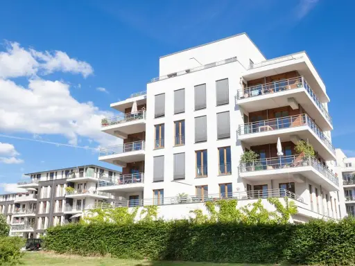Immeubles modernes avec balcons fleuris, sous un ciel bleu. Un projet immobilier qui pourrait bénéficier de la loi Borloo pour son accessibilité.