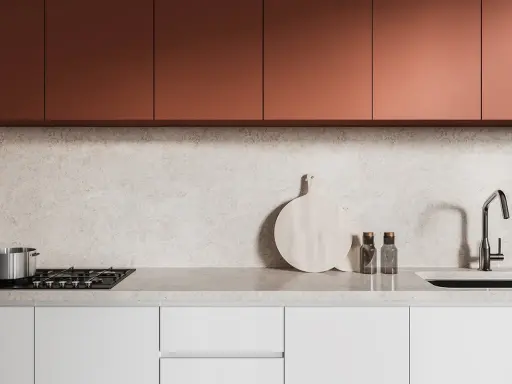 Crédence de cuisine moderne avec placards cuivrés, plan de travail en marbre clair, plaque de cuisson, évier et ustensiles.