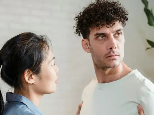 Un homme au regard intense, peut-être un pervers narci, semble ignorer une femme qui le regarde avec inquiétude.