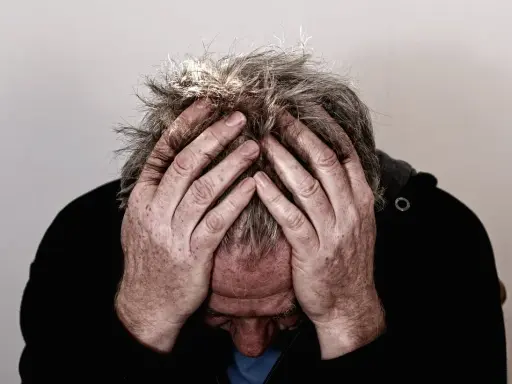 Uomo con le mani tra i capelli grigi, testa china, espressione di profonda preoccupazione. Mala tempora currunt sed peiora parantur.