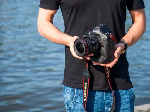 Mężczyzna trzyma aparat Canon EOS-1D Mark II z obiektywem, idealny do fotografii krajobrazowej dzięki matrycy **APS-C**.