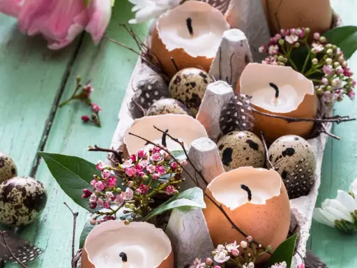 Osterdeko selber basteln mit Naturmaterialien: Eierschalenkerzen, Wachteleier und zarte Blüten auf Holz.