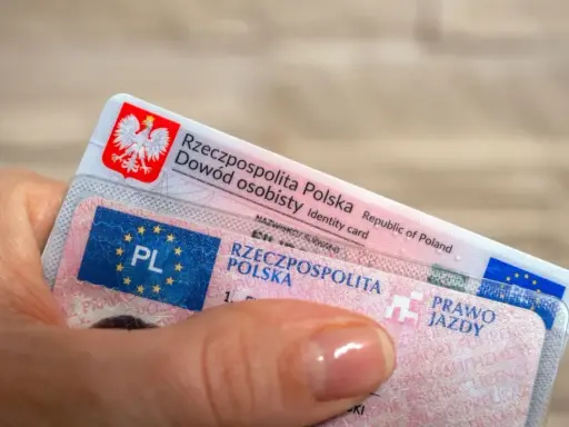 Dłoń trzyma polski dowód osobisty i prawo jazdy. Czas na wymianę prawa jazdy bezterminowego?