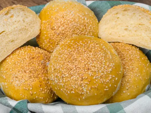 Koszyk pełen pysznych, złotych bułek bez drożdży, posypanych sezamem. Idealne na burgery lub jako dodatek do posiłku.