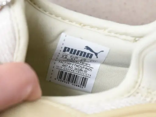 Oryginalna metka Puma na jasnej podeszwie buta, z informacjami o rozmiarze i pochodzeniu.