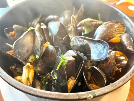 Un plat fumant de moules, prêtes à être dégustées. Un accompagnement moules parfait pour un repas savoureux.
