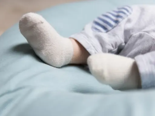 Ciepłe stópki w skarpetkach na jasnoniebieskim tle. Czy dziecko powinno spać w skarpetkach?