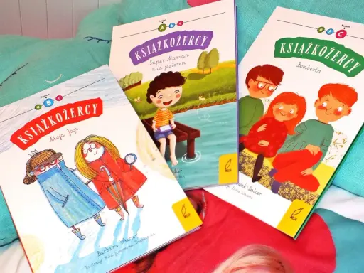 Trzy okładki książek z serii "Książkożercy" na miękkim, turkusowym tle. Dwie dziewczynki i chłopiec, bohaterowie przygód, zapraszają do czytania.
