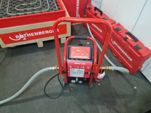 Equipo ROTHENBERGER para limpieza suelo radiante. Máquina roja con mangueras y maletines a juego.