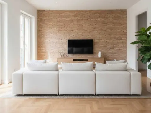 Sofá blanco modular frente a pared de ladrillo y mueble de TV. La **dirección de obra** supervisó este moderno y acogedor salón.
